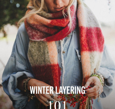 Blonde woman wearing a red, olive and orange scarf in a denim dress with a tree behind her. Text includes, "Winter Layering 101" and "Read Now"