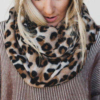 Person wearing a leopard print scarf with a neutral background
