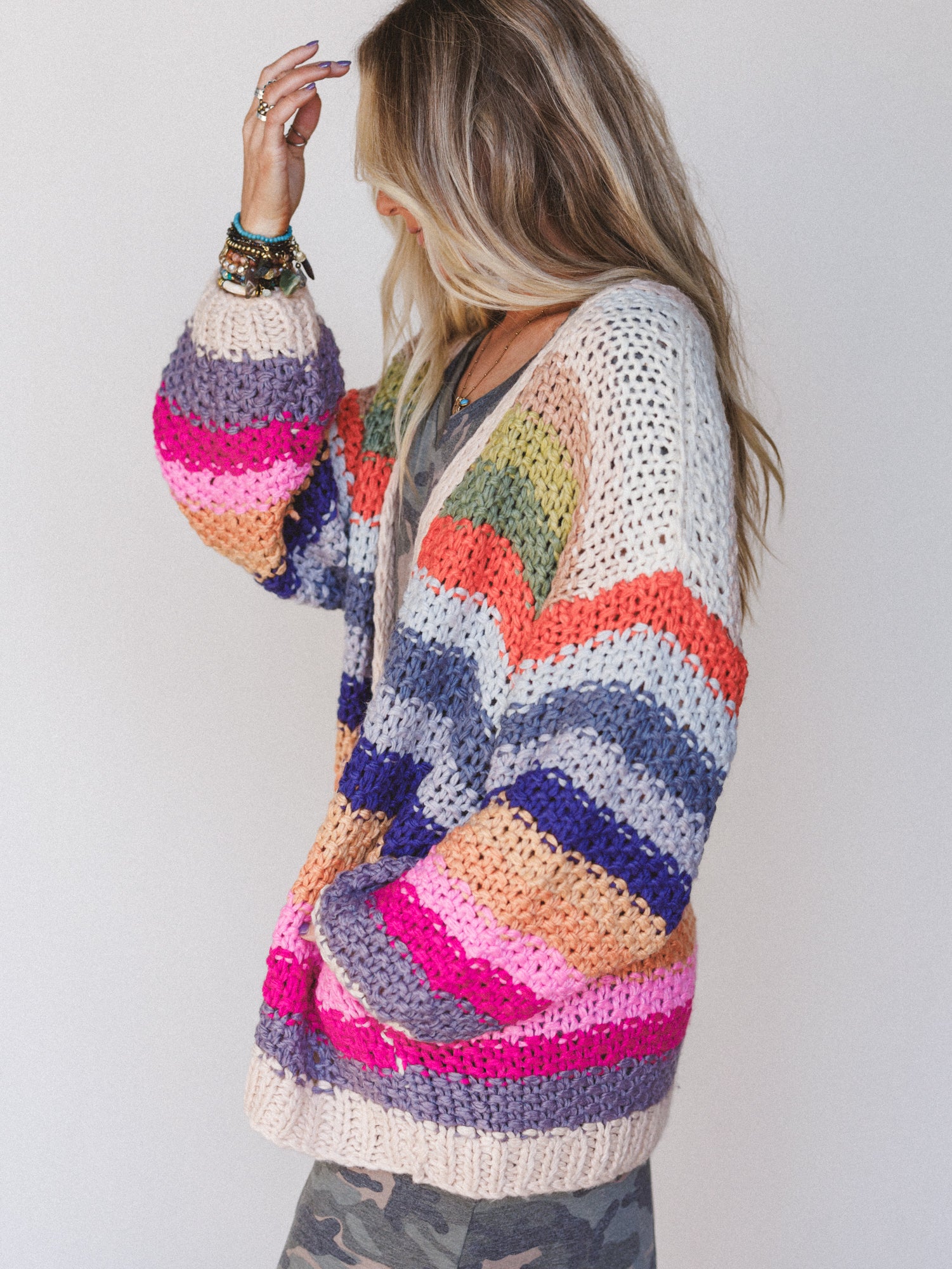 Woman wearing a colorful crochet cardigan against a plain background