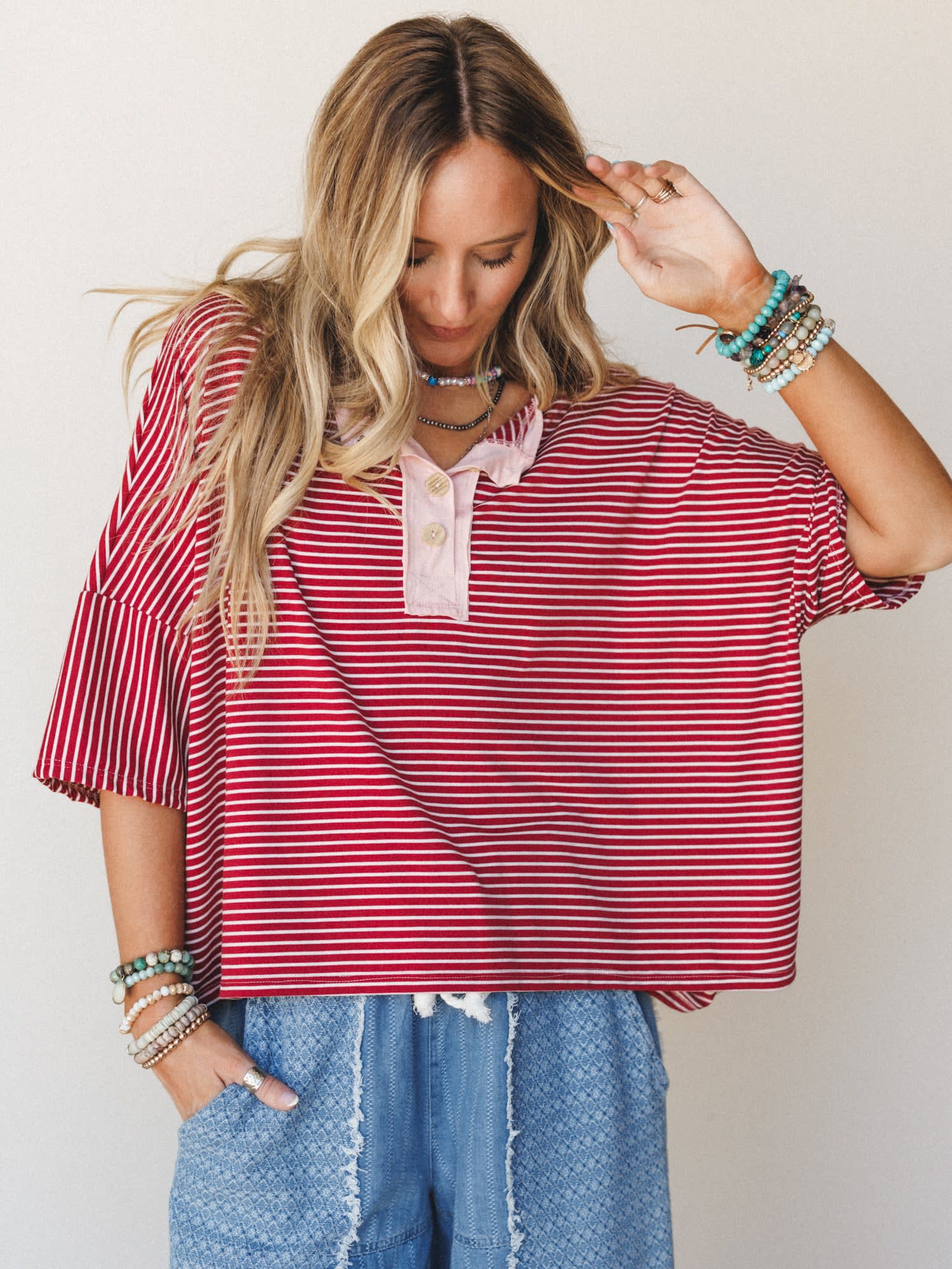 A relaxed oversized striped top in marsala and white styled with textured denim shorts and stacked boho bracelets — the kind of effortless outfit that looks like you just threw it on and somehow nailed it.