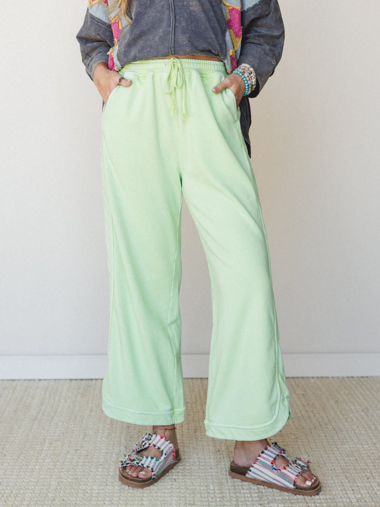 Wide-leg mint green sweat pants styled with beaded sandals and a graphic jacket — the kind of outfit that looks effortless but is clearly very much on purpose.