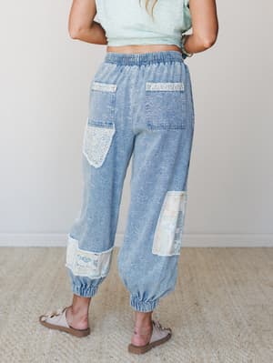 Shot from behind, these light-wash denim joggers feel like a weekend discovery — all floral burnout texture, lace patchwork, and elastic cuffs that somehow make casual feel completely intentional.