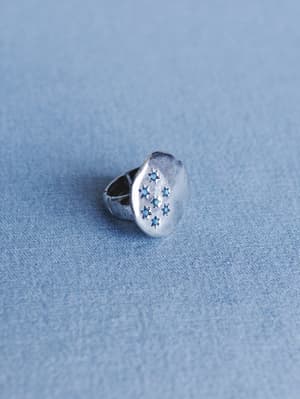 Silver ring with star designs on a blue textured background