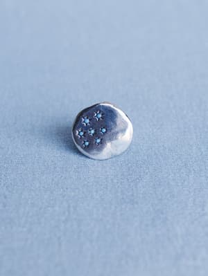 Silver button with star design on a light blue background