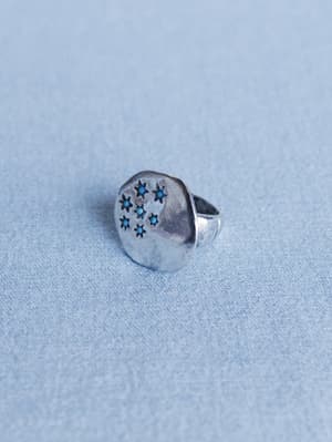 Silver ring with star designs on a light blue textured background