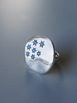 Silver ring with blue star-shaped stones on a gray background
