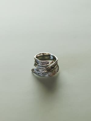 Silver feather-shaped ring on a light gray background