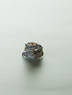 Silver feather-shaped ring on a light gray background