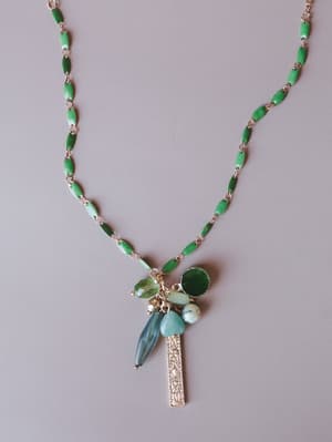 A long pendant necklace with a green enamel oval-link chain leading to a mixed stone cluster — layered teardrop and round gemstones in varying shades of green and blue-gray, finished with an engraved gold bar charm.