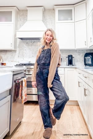 Person wearing denim overalls in a kitchen