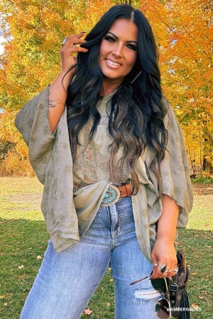 Woman standing outdoors with autumn foliage in the background