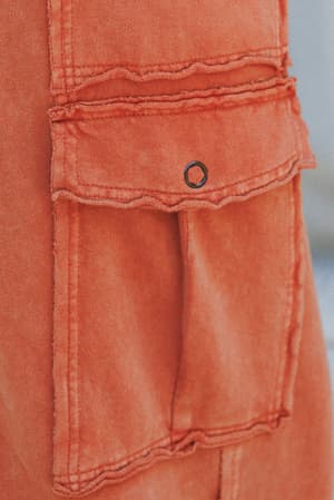 Close-up of the Game On Cargo Wide Leg Pant in burnt orange, featuring a denim pocket with frayed edges and a black metal snap button on the flap for a relaxed, boho-cargo look.