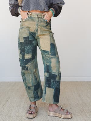 Acid-washed barrel jeans covered in patchwork denim panels styled with a cropped gray sweatshirt, stacked turquoise bracelets, and platform espadrille sandals — the kind of pants that do all the talking.