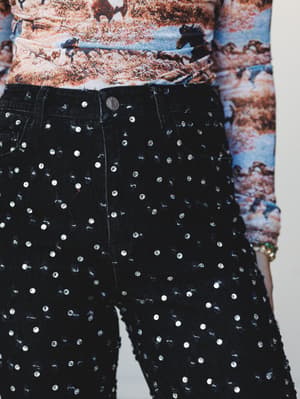 A close crop of black rhinestone-studded jeans paired with a wild horse graphic top — the kind of outfit that makes a Tuesday feel like an event.