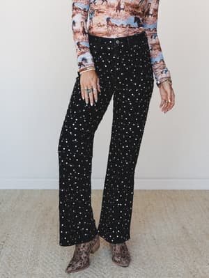 Black flare jeans covered in allover silver sequin embellishment styled with a wild horse print long-sleeve top and leopard ankle boots — the kind of outfit that does the talking for you.