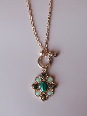 A gold chain necklace with a toggle closure and a multi-stone pendant featuring a center malachite cabochon surrounded by tiger's eye and mint green stones in a floral cluster setting — the kind of piece that looks like it came from someone's well-tr