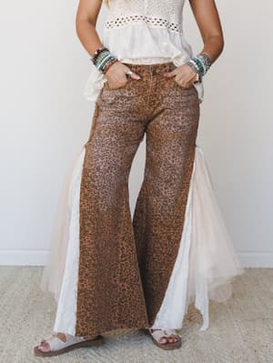 Leopard print wide-leg flare pants with eyelet lace side panels styled with a crochet crop top, stacked beaded bracelets, and sandals — boho maximalism that means business.