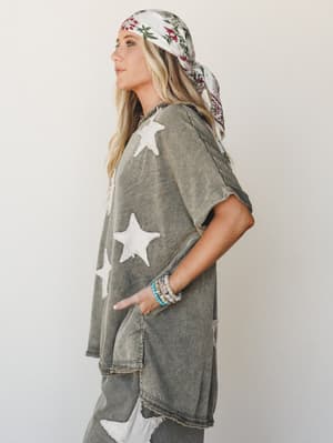 An oversized acid-wash olive set with chenille star appliqués, styled with a floral head scarf and stacked bead bracelets — the kind of outfit that looks effortless but is clearly very intentional.