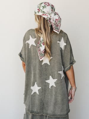 Shot from behind, this acid-washed olive set with chunky raw-edge star appliqués has that perfectly worn-in, effortlessly cool energy — styled with a floral head scarf and silver rings for a look that feels collected without trying.
