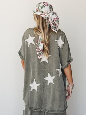 Shot from behind, this acid-washed olive set with chunky raw-edge star appliqués has that perfectly worn-in, effortlessly cool energy — styled with a floral head scarf and silver rings for a look that feels collected without trying.