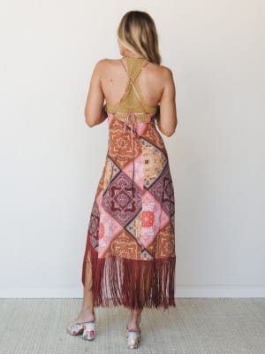 Shot from the back, this midi dress makes a statement with patchwork bandana print panels, a crochet racerback bodice, and long burgundy fringe hem — paired with floral block-heel mules for a free-spirited, festival-ready feel.