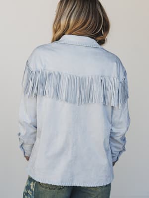 Light blue denim jacket with fringe details on a plain background