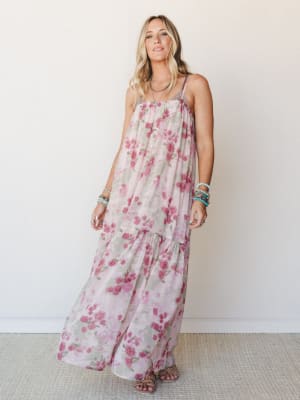 A flowy floral maxi dress in soft mauve and rose tones styled with stacked beaded bracelets and strappy sandals — the kind of dress that makes even a Tuesday feel like something.