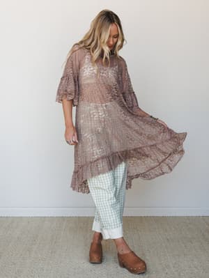 A flowy taupe lace tunic layered over sage gingham cuffed pants and brown platform clogs — the kind of outfit that looks effortless but was absolutely thought about.