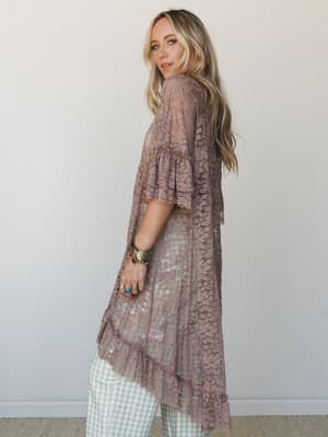 A long lace kimono duster in warm taupe layers over mint gingham pants, styled with stacked boho jewelry for a look that feels equally at home at a summer wedding or a weekend farmers market.