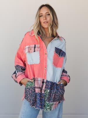 A patchwork oversized button-down shirt in coral, powder blue, navy floral, green botanical, and pink plaid — the kind of piece that looks like it was made from all your favorite vintage fabrics at once, worn casually over light wash jeans with a sil