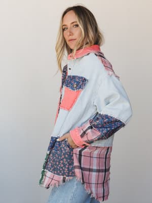 A model shot in three-quarter profile against a soft neutral studio wall, wearing a patchwork oversized jacket layered over light wash jeans — the kind of piece that looks like it was stitched together from the prettiest parts of your grandmother's f