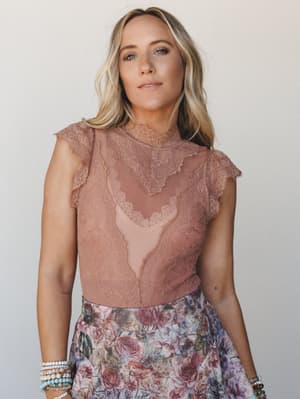 A lace bodysuit in warm terracotta pairs with a floral skirt for a look that feels romantic without trying too hard — the kind of outfit you wear when you actually want to be there.