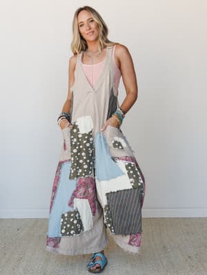 A wide-leg patchwork jumpsuit in light taupe worn over a blush pink tank, layered with beaded bracelets and a silver necklace — the kind of outfit that looks like it was sewn together from your favorite vintage finds.