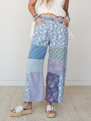 Patchwork wide-leg jeans in a mix of daisy, paisley, and solid denim panels styled with a cropped white top and platform espadrille sandals — free-spirited and full of personality.