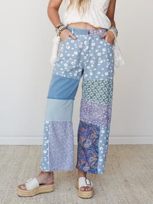 Patchwork wide-leg jeans in a mix of daisy, paisley, and solid denim panels styled with a cropped white top and platform espadrille sandals — free-spirited and full of personality.
