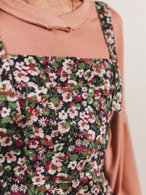 Floral apron over a pink shirt on a neutral background