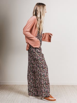 Woman wearing a floral dress and pink cardigan against a plain background