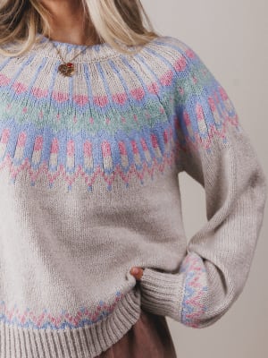 Close-up of a person wearing a patterned sweater with a neutral background