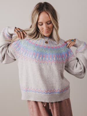 Woman wearing a gray sweater with colorful pattern on a plain background