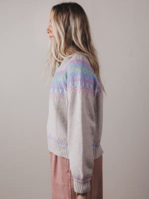 Person wearing a patterned sweater with a neutral background