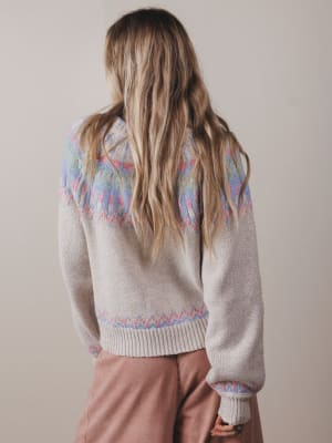 Person wearing a patterned sweater with a neutral background