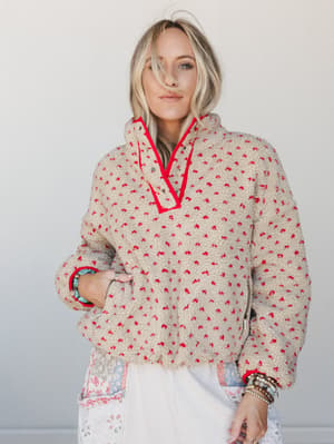 A cozy sherpa pullover in oatmeal and red speckle print with contrast red trim gets layered over a floral-print skirt, styled with a stack of boho bracelets — the kind of outfit that says 'I got dressed on purpose but I'm still comfortable.'