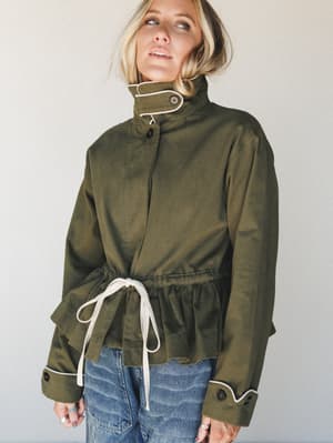 An olive utility jacket with cream contrast trim and a drawstring waist gives off that perfectly undone, intentional energy — styled over relaxed denim for a look that feels as good as it looks.