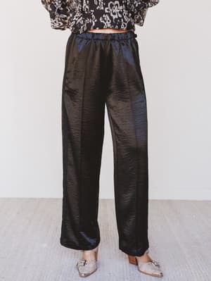 Black satin pants worn by a person on a light gray background