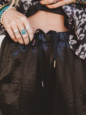 Person wearing a black outfit with jewelry, including rings and bracelets.
