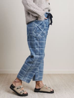 Person wearing blue plaid pants and a gray sweater on a plain background