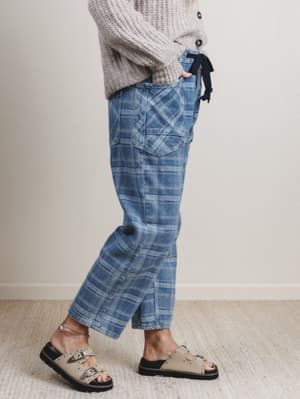 Person wearing blue plaid pants and a gray sweater on a plain background