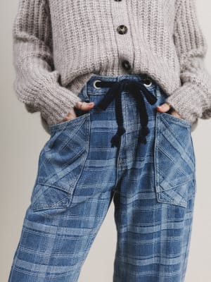 Person wearing a gray knit cardigan and blue plaid pants with a black drawstring.