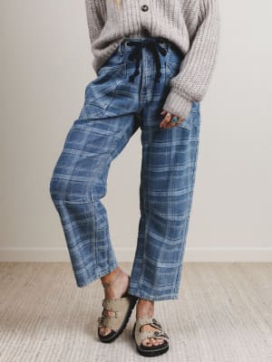 Person wearing blue plaid pants and a gray sweater on a neutral background
