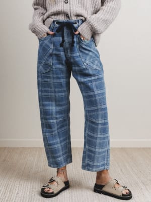 Person wearing blue plaid pants and a gray sweater indoors.